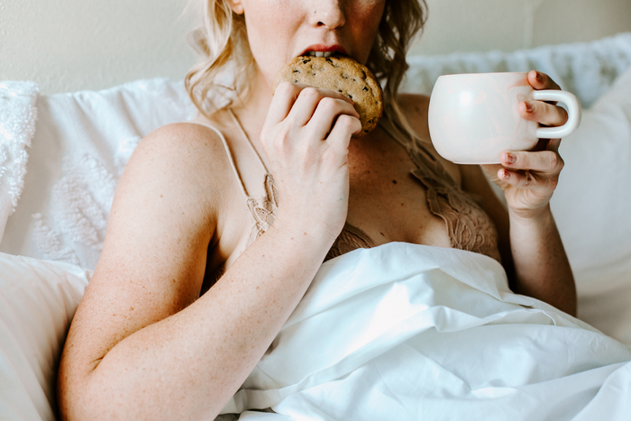 Woman sitting in bed with food cravings